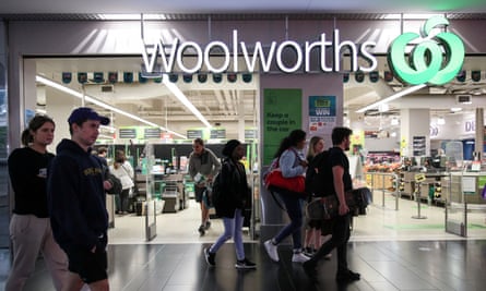 People walk past a Woolworths supermarket