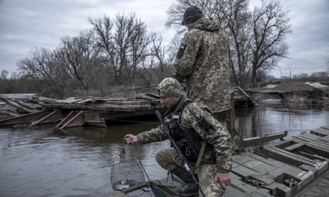 Ukrainian servicemen fish near a destroyed bridge in the Bakhmut region.