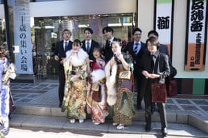 Young women in Tokyo wear kimonos, alongside men in suits