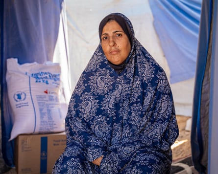 Woman sits next to a sack of flour and ration boxes