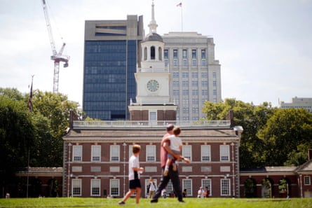 people walk through grass outside brick building