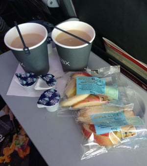 On a Virgin flight: plastic stirrer, single serve milk, plastic cup and a sliced apple covered in plastic