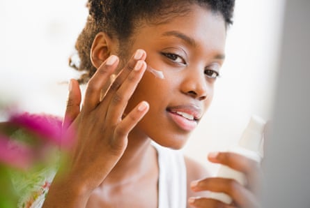 A woman applies face lotion