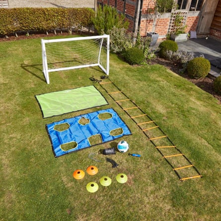 A football goal, target nets, agility ladder, cones and ball laid out on grass