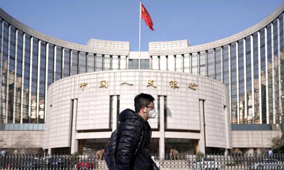 Man wearing a mask walks past the headquarters of the People’s Bank of China in Beijing.