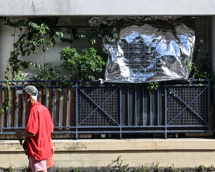 A man walks past a window covered by a silver foil blanket