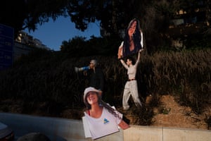 Activists block a highway in Tel Aviv while holding photographs depicting the faces of Israeli women who are being held hostage in the Gaza Strip during a protest demanding their release from Hamas captivity