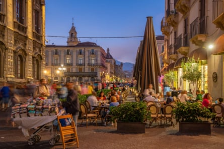 busy and colourful Sicily street scene at dusk, people are dining at outdoor tables