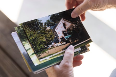 Two hands hole a pile of photographs of a home getting a demolished