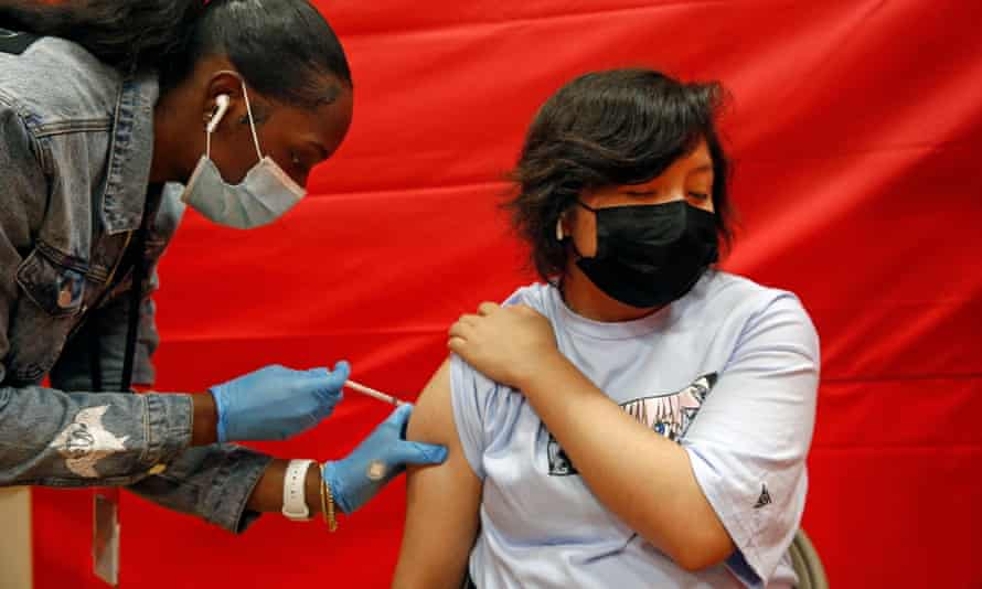 Alex Olvera, 15, is vaccinated with Pfizer by Rickeyva Foster, left, at the Manual Arts high school on 17 May 2021 in Los Angeles.