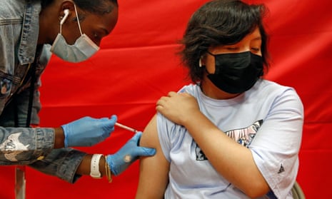 Alex Olvera, 15, is vaccinated with Pfizer by Rickeyva Foster, left, at a high school in Los Angeles.