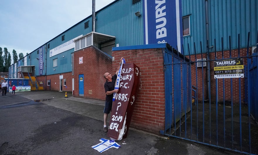 A supporter places a scarf atop a coffin left outside Gigg Lane on the day of Bury FC’s expulsion from the Football League
