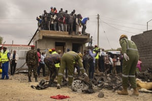 A large number of people have gathered on the roof as rescue teams go through visible fragments, including a burnt vehicle wheel and twisted wreckage of a crashed aircraft ambulance in Mwihoko village northern Nairobi.
