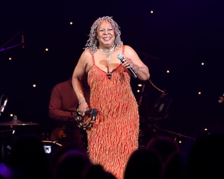 Martha Reeves on stage, wearing a shiny orange dress and holding a tambourine
