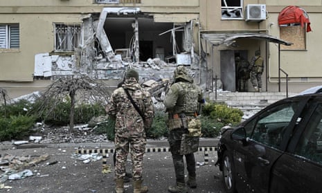 Ukrainian policemen stand in front of a damaged residential building after a Russian shelling in Kherson, southern Ukraine, on 29 January 2023.
