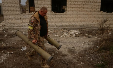 A Ukrainian serviceman carries captured anti-tank grenade launchers at a former position of Russian forces in Blahodatne village in the Kherson region, southern Ukraine