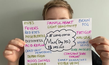 A child holds up a sign with his symptoms on it in front of his face
