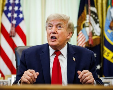 Donald Trump answers reporter’s questions after signing an executive order on auto repairs in the Oval Office of the White House, with flags included the stars and stripes behind