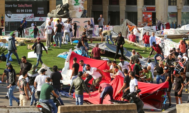 Protesters run as others destroy tents at a camp set up at an anti-government demonstration in central Beirut on Tuesday.
