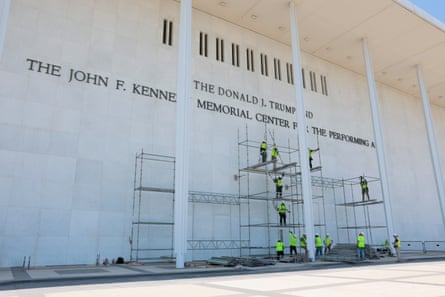 Construction workers build scaffolding near the sign