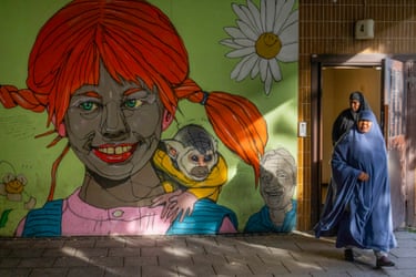 Two Muslim women walk past a mural of Pippi Longstocking