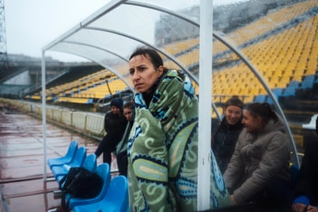 Yana Vynorukova, Mariupol’s president, watches from the dugout in a blanket