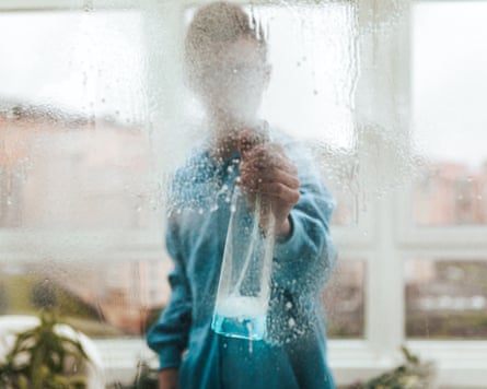 Young male cleaning windows at home