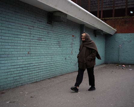 A woman walks past a shabby looking building