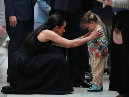 Meghan with her hands on a shy toddler’s shoulders