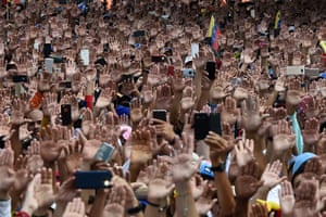 People raise their hands at a rally in Caracas, Venezuela
