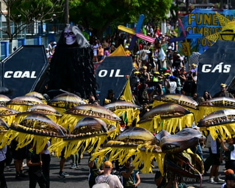 People in bright costume carry coffins labelled coal, oil and gas in a parade