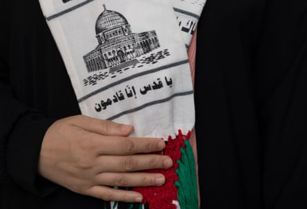 Salma holds a Palestinian scarf that is wrapped around her neck