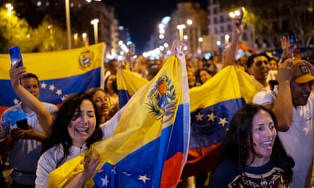 Venezuelan nationals hold up their national flag during a protest at night in central Barcelona