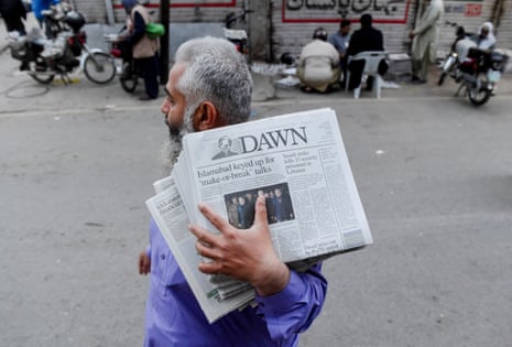 A man carrying a bundle of newspapers with a headline that reads, “Islamabad keyed up for ‘make-or-break’ talks”, walks along a street, as delegations from the United States and Iran are expected to hold high-stakes talks, Lahore, Pakistan.