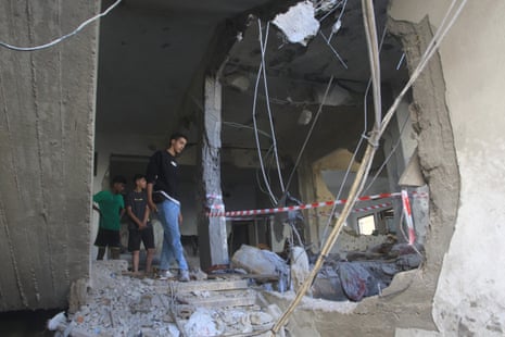 Three people stood inside a destroyed home.