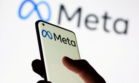 Woman holds smartphone with Meta logo in front of a displayed Facebook's new rebrand logo
