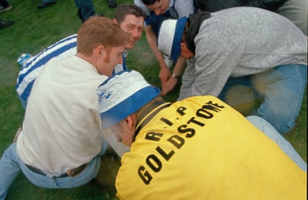 Brighton fans, one wearing a shirt with RIP Goldstone on the back, dig up the turf
