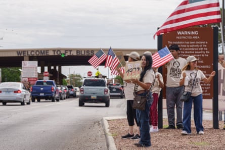 People hold signs and wave American flags outside an army base.