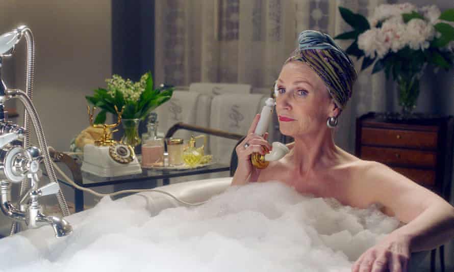 Lynch on the phone in full make-up, in a bathtub full of bubbles, as Sophie Lennon in The Marvelous Mrs Maisel (2019).