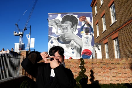 A Tottenham Hotspur fan poses for a photo in front of mural of Son Heung-min.