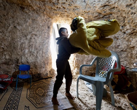 दक्षिणी इज़राइल में अराद के पास एक अज्ञात बेडौइन गांव में एक बेडौइन लड़का एक गुफा की सफाई कर रहा है जिसे उसने एक अस्थायी बम आश्रय स्थल में बदल दिया है।