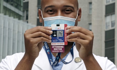 Alister Martin, an emergency room doctor at Massachusetts General Hospital, holds up a voter information card he wears on his ID.