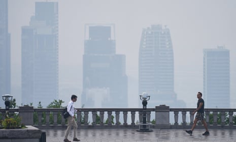 People walk near a balustrade at a scenic point of the Mount Royal mountain overlooking the city of Montreal shrouded in haze of smog, on Monday.
