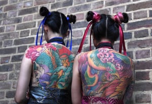 Tattoo enthusiasts pose for photographs during the London Tattoo Convention at Tobacco Dock