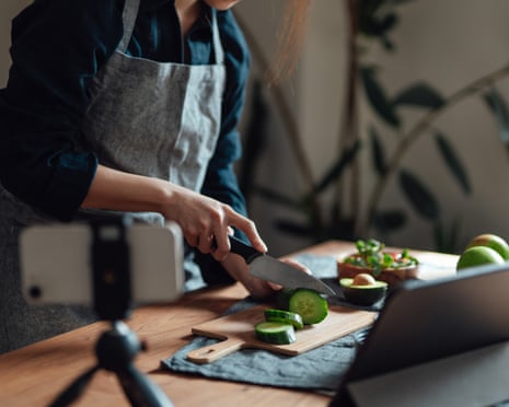 A person making a recipe while looking at a tablet and taking a video on their phone