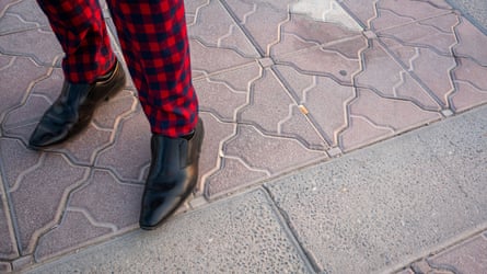 Close-up image of a man wearing red-and-black checked trousers and black pointed shoes on the Corniche in Doha, Qatar.