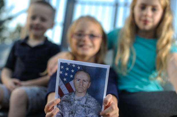 The children of Captain Michael Jackson, who is currently deployed from Fort Drum, hold up a photo of their father.