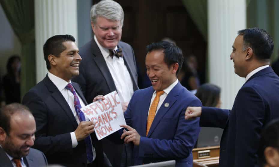 Assemblyman Miguel Santiago presents assemblyman David Chiu, a note reading #PUBLIC BANKS NOW after the assembly approved Chiu’s measure legalizing public banking. 