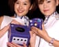 Two women holding the purple GameCube console and controller at an event in Tokyo in August 2001
