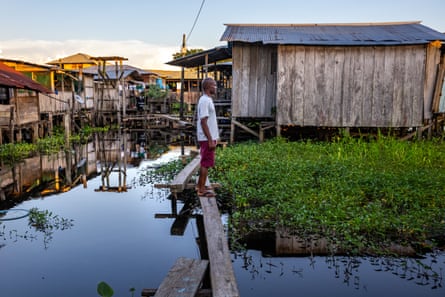 Aparicio Vásquez stands on a wooden board watching the flooded area